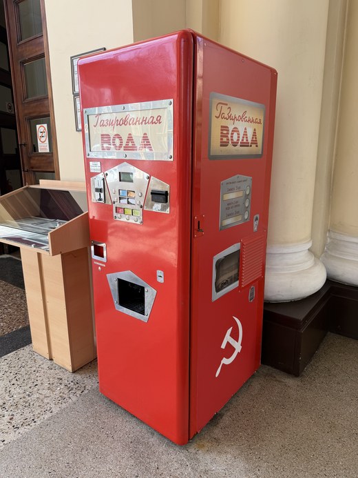 A restored red Soviet-era soda water vending machine with a hammer and sickle emblem, Yerevan Railway Station, Armenia