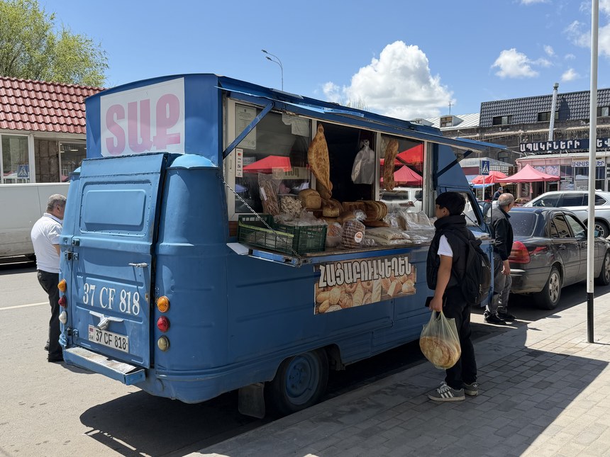 A customer buying fresh bread from a vintage blue bread truck, Gyumri, Armenia