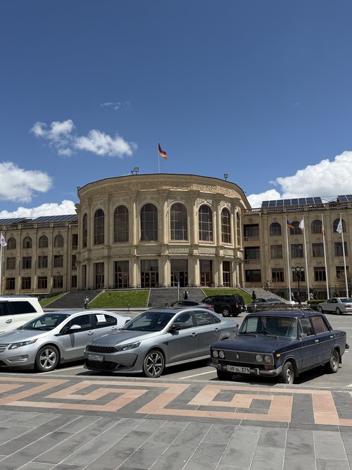 Cars parked before a curved colonnaded municipal building flying the Armenian flag, Vardanants Square, Armenia