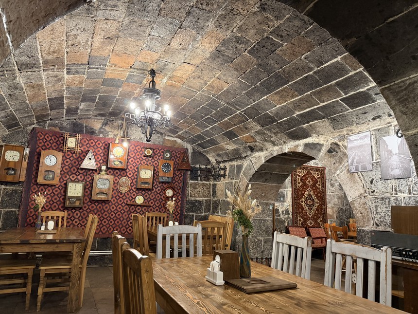 A vaulted stone cellar restaurant decorated with antique clocks and wooden tables, Gyumri, Armenia