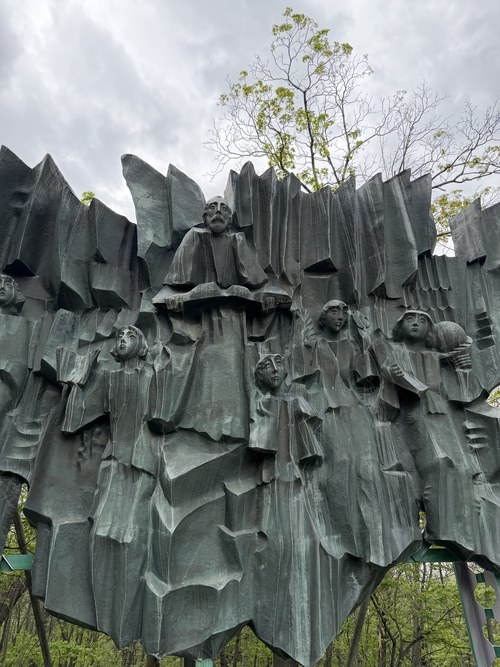 An abstract bronze sculpture of faces emerging from jagged rock-like forms, Central Park, Armenia