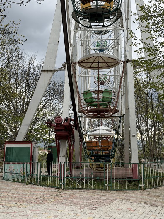 The colorful cars of an old ferris wheel behind a fenced enclosure, Central Park, Armenia