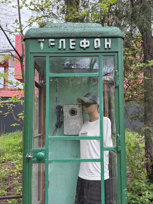 A traveler using an old green Soviet-era telephone booth, Central Park, Armenia