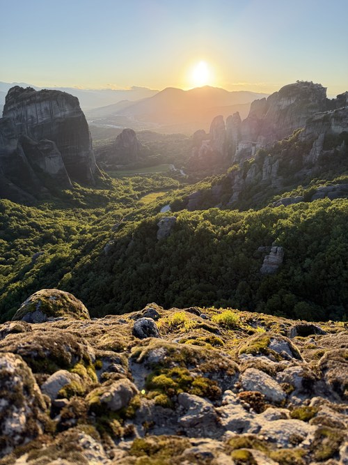 Sunset over a forested valley and rock pillars, mossy stone ahead, Main Observation Deck of Meteora, Greece
