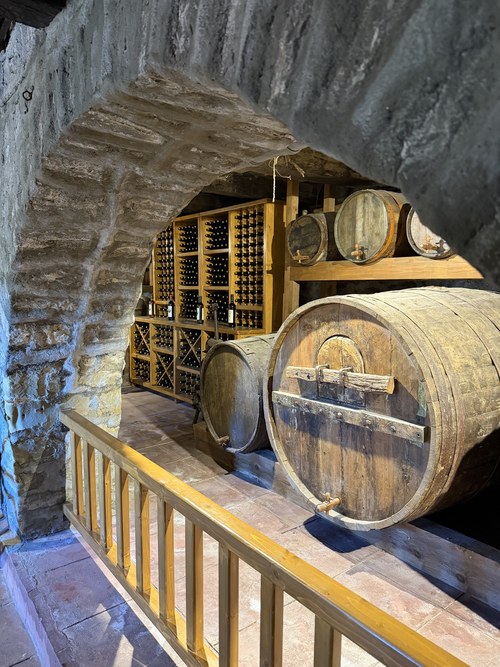 Large wooden wine barrels and shelves of bottles seen through a stone archway, Great Meteoron, Greece