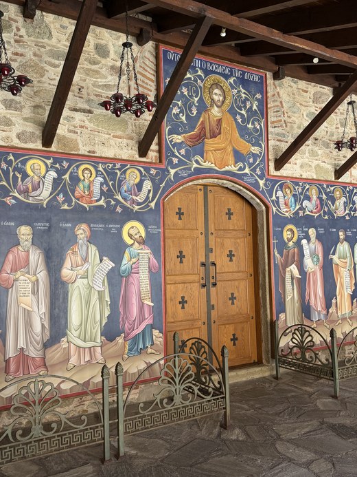 Colorful religious frescoes of saints around a wooden door with cross panels, Great Meteoron, Greece