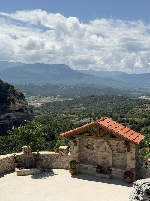 Small stone shrine with a tiled roof on a terrace overlooking forested hills and mountains, Holy Spirit Rock hike, Greece