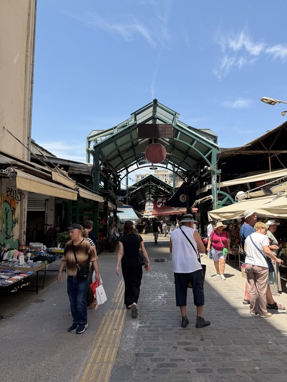 Shoppers walking under the covered entrance archway of a market street, Kapani Market, Greece