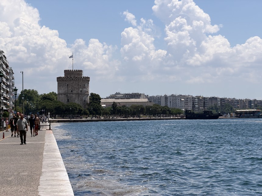 The White Tower seen across the water along a waterfront promenade with pedestrians, Greece