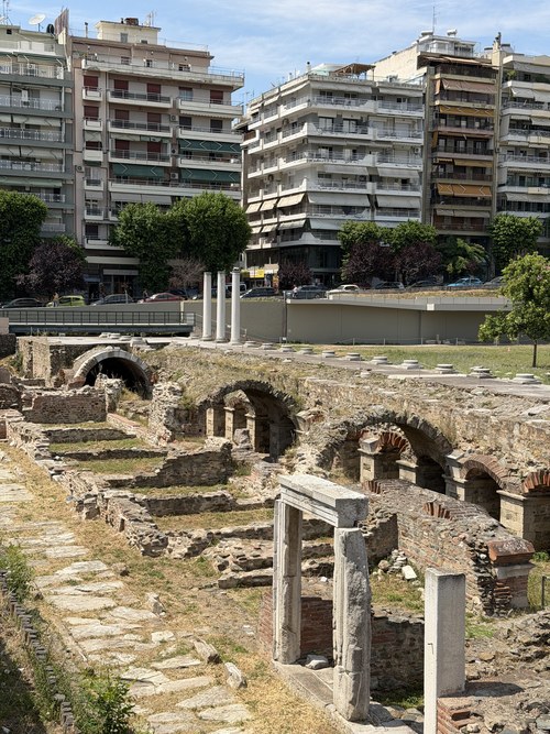 Excavated brick arches and stone columns beside apartment buildings, Holy Church of St. Demetrius, Greece