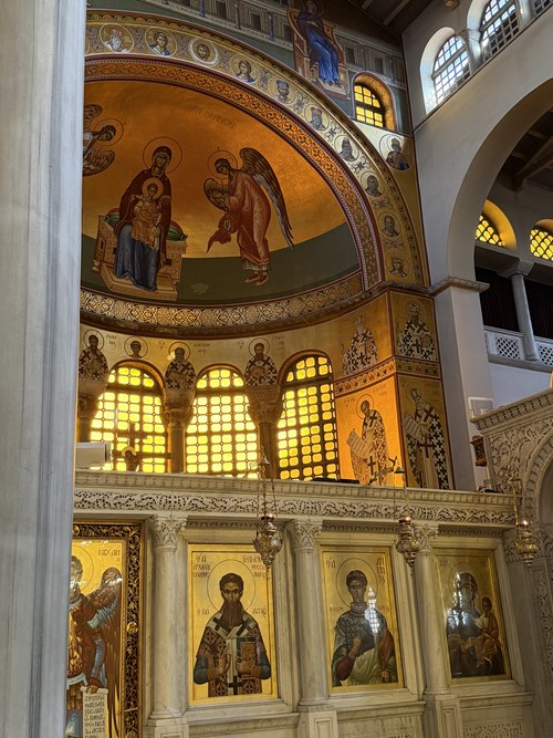 Golden apse mosaic of the Virgin and Child with an angel above glowing windows and icon panels, Thessaloniki, Greece