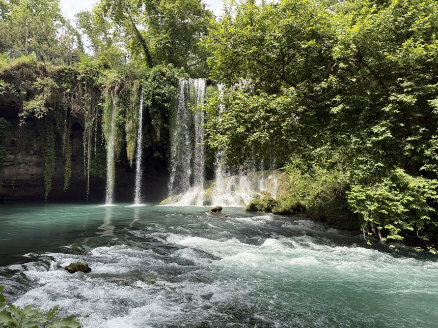Waterfalls dropping from a leafy cliff into a turquoise pool with white rapids, Upper Düden Falls, Turkiye