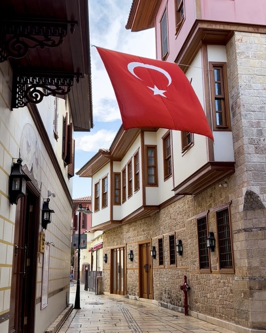 Turkish flag hanging over a narrow cobbled street of restored Ottoman houses, Kaleiçi Old Town, Antalya, Türkiye