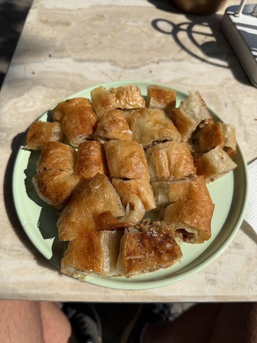 Plate of golden flaky pastry rolls cut into pieces on a sunlit marble table, Fethiye, Turkiye