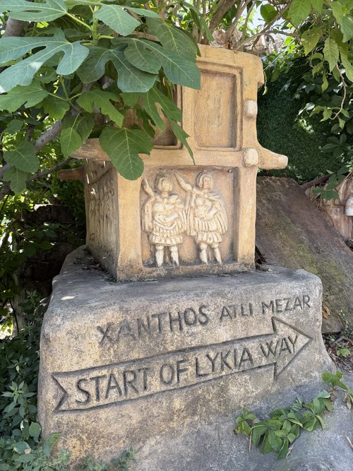 Stone marker with carved figures and an arrow reading "Start of Lykia Way," Ancient City of Telmessos, Turkiye