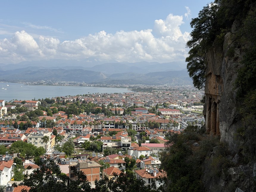View over red-roofed houses and the bay from a cliff with rock-cut tomb facades, Ancient City of Telmessos, Turkiye