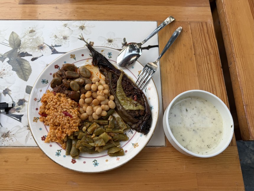 Plate of stuffed eggplant, bulgur, white beans, fava beans and green beans beside a bowl of yogurt, Gözlemeci Sema, Turkiye