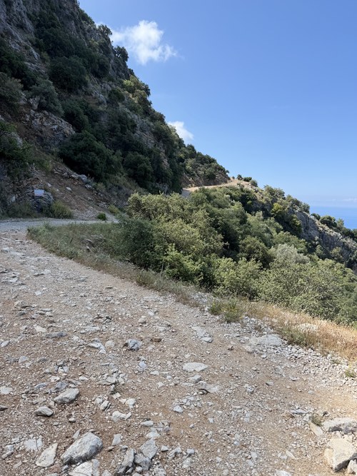 Rocky gravel trail winding along a scrubby mountainside above the sea, Montana Seyir Tepesi, Ölüdeniz, Turkiye