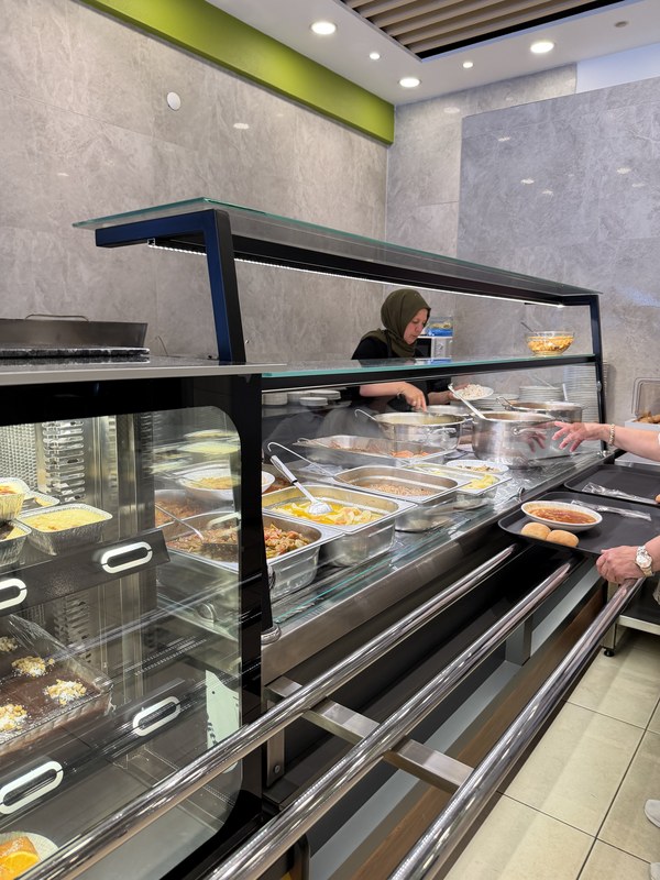 Cafeteria-style counter of home-cooked dishes with a cook behind it, Yeşil Asma Yaprağı Ev Yemekleri & Meze, Turkiye