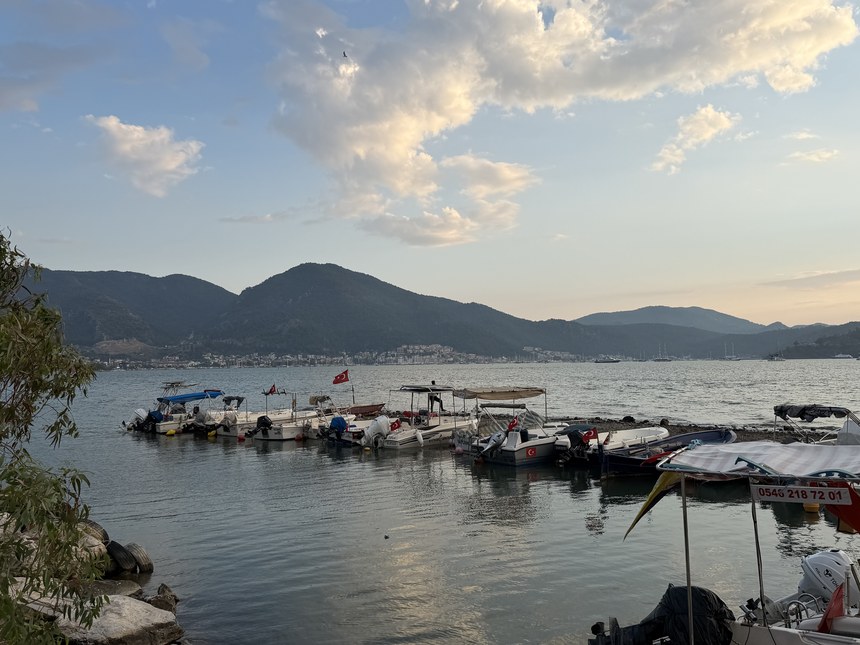 Small fishing and tour boats moored in a calm bay at dusk, with hills and the town across the water, Fethiye, Turkiye